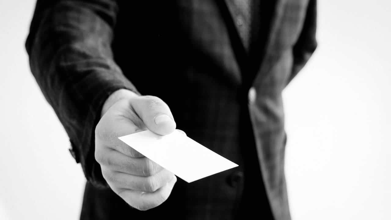 A black and white photo of a businessman holding his business card