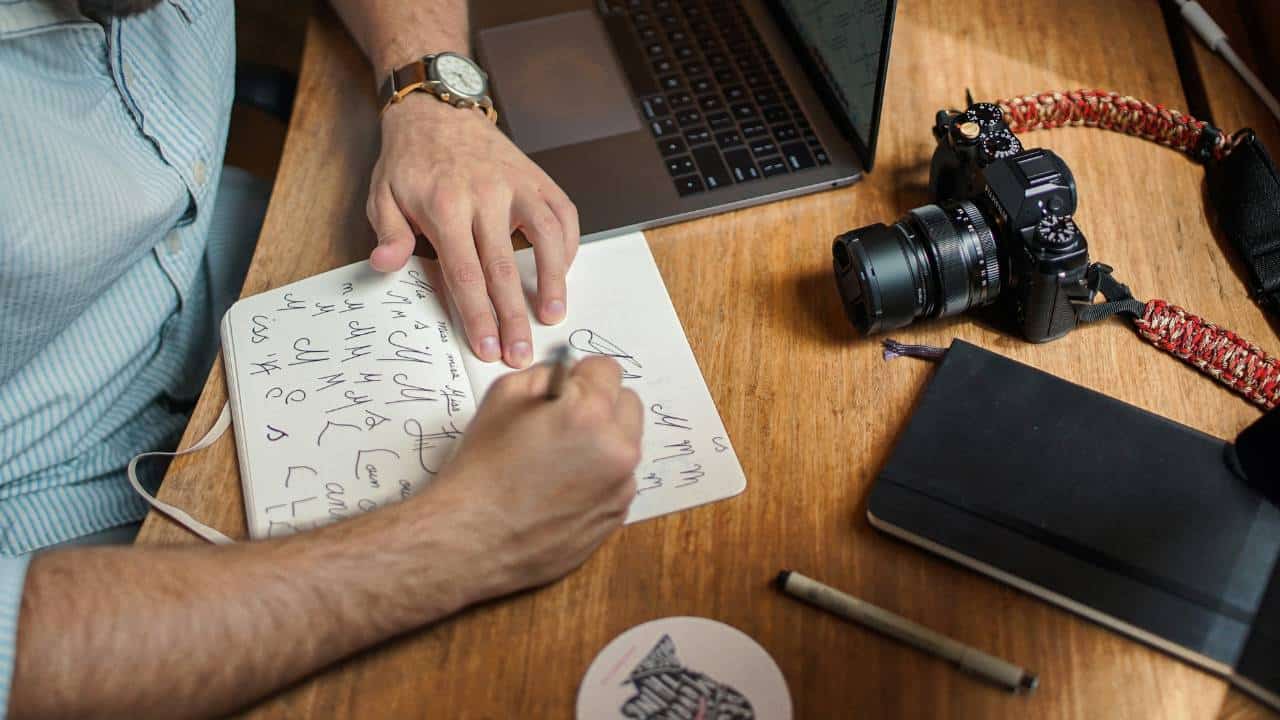 A man using a pen and a notebook to create an eye-catching logo