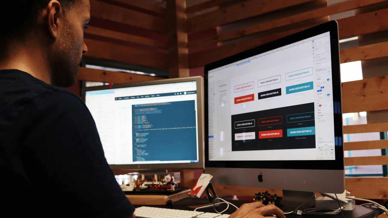 A man using a dual monitor setup to design a website