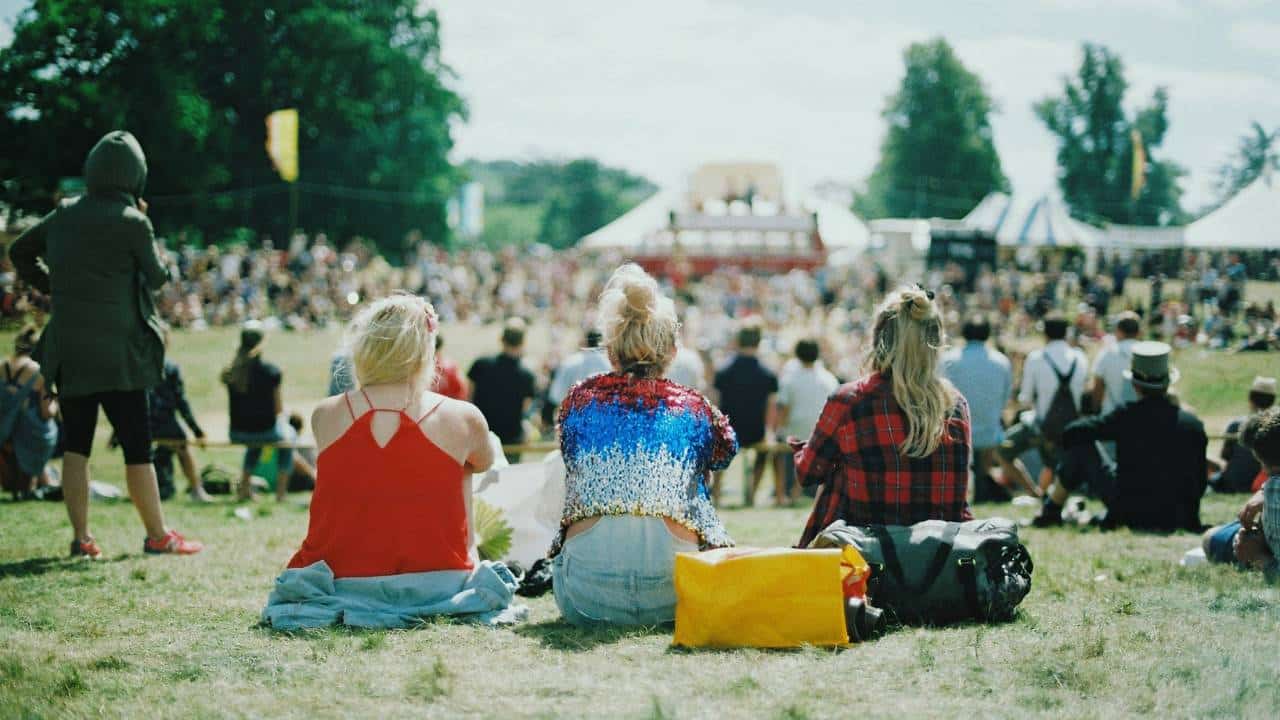 Three women sitting on the ground at a music festival