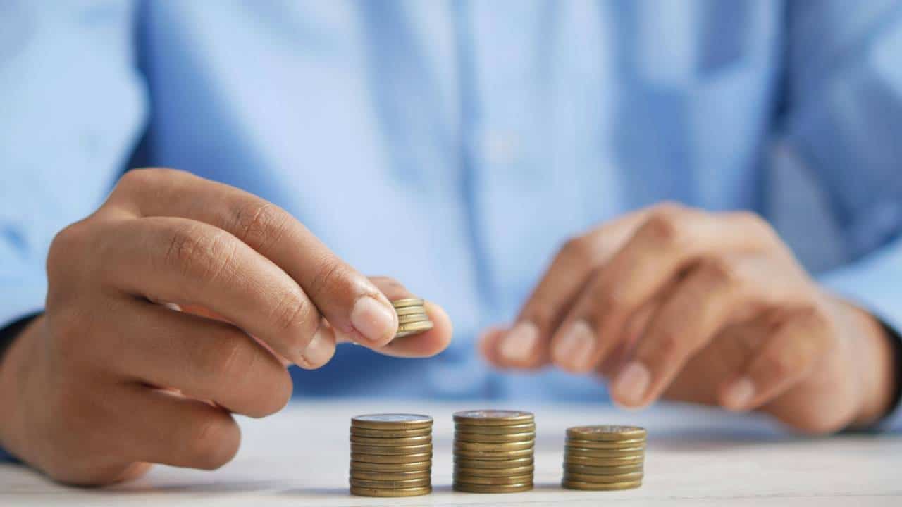 A person in a blue shirt stacking several coins on top of each other