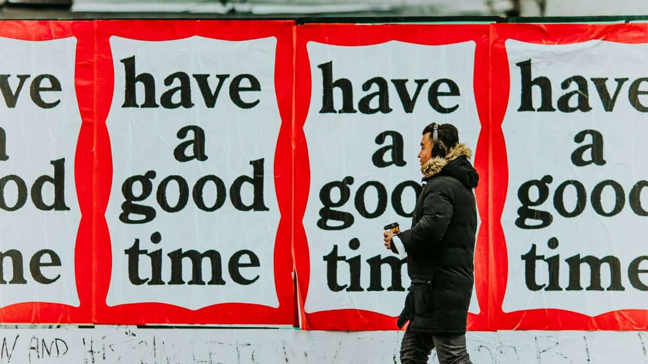 A man walking next to large "have a good time" posters
