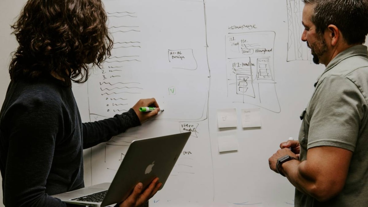 A woman and a man using a whiteboard in the conference room